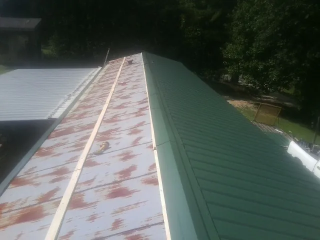 Old rusted panels beside newly installed green metal roofing — Wind Damage Roof Repair by Roofing Brothers in Belle Mead