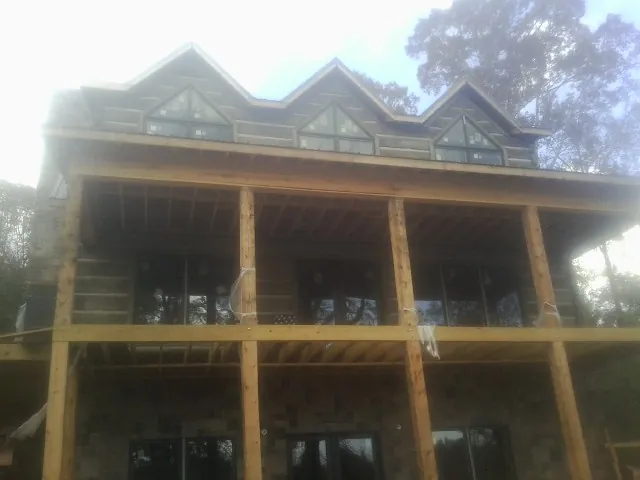 Dormers and porch framing on a large log home under construction — Roof Coating work by our crew in Belle Mead