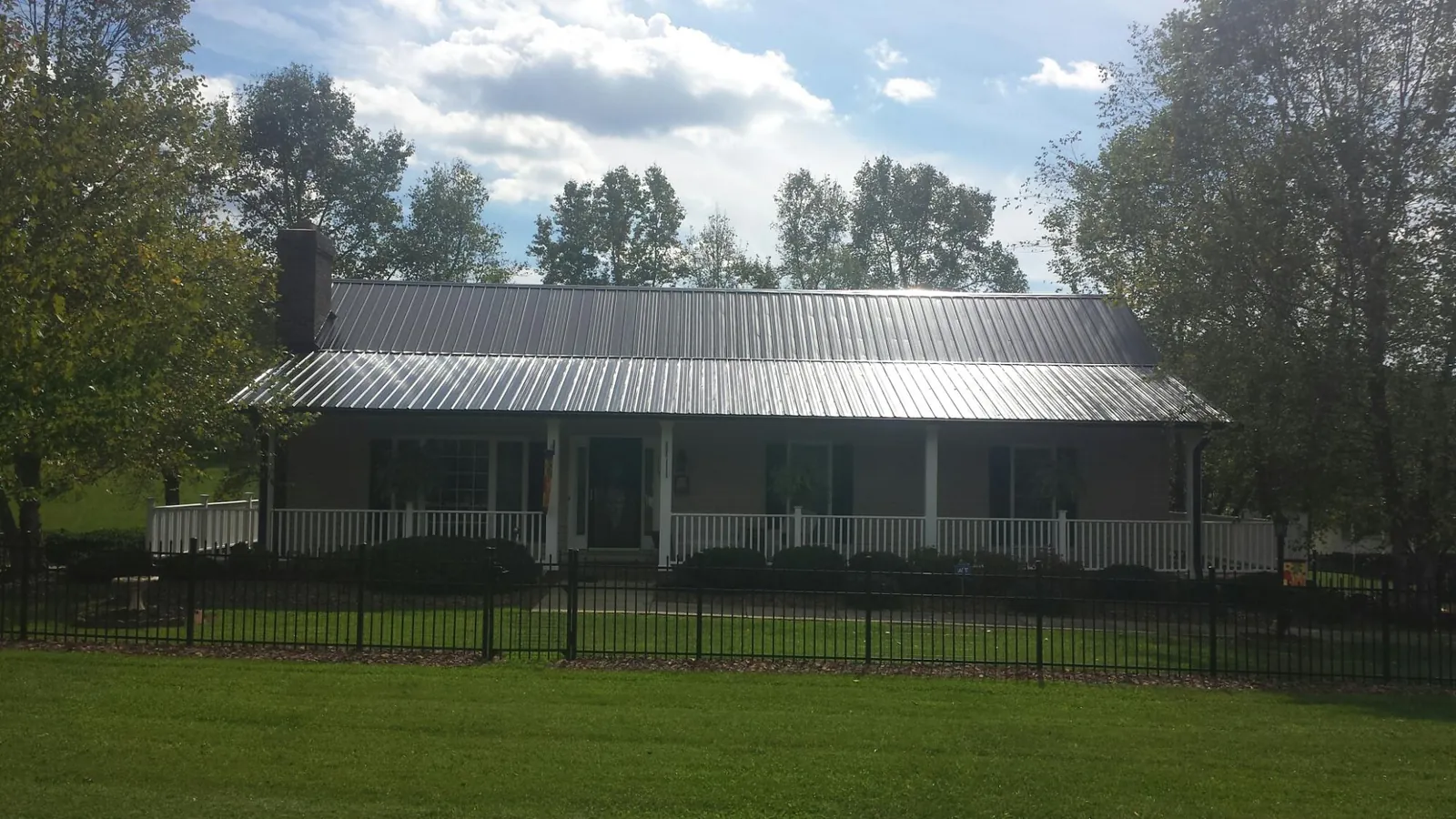 Gray metal roof on a brick ranch with a full width front porch — Gutter Guard Installation work by our crew in Belle Mead