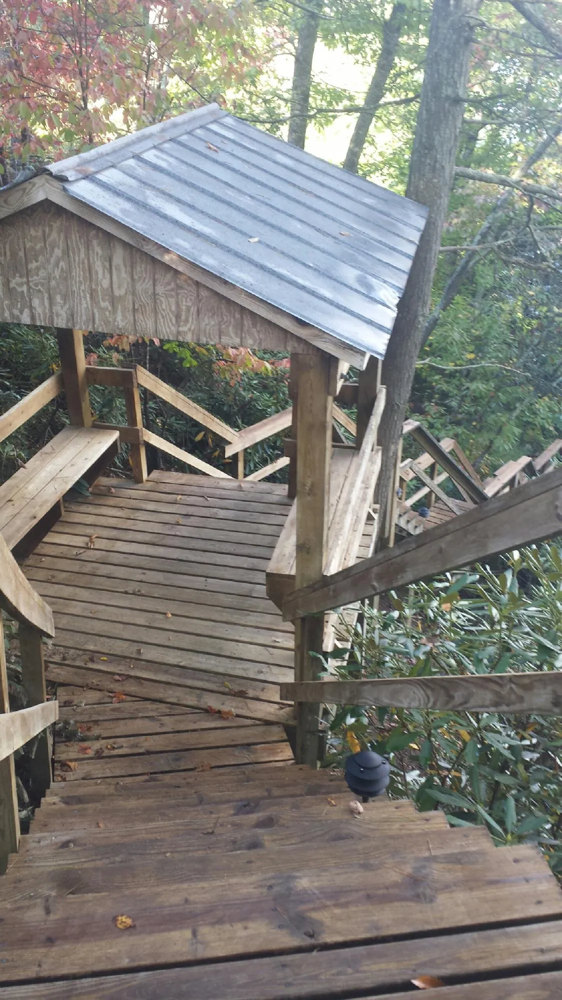 Metal roofed shelter over wooden steps on a wooded walkway — Skylight Repair & Installation work by our crew in Belle Mead
