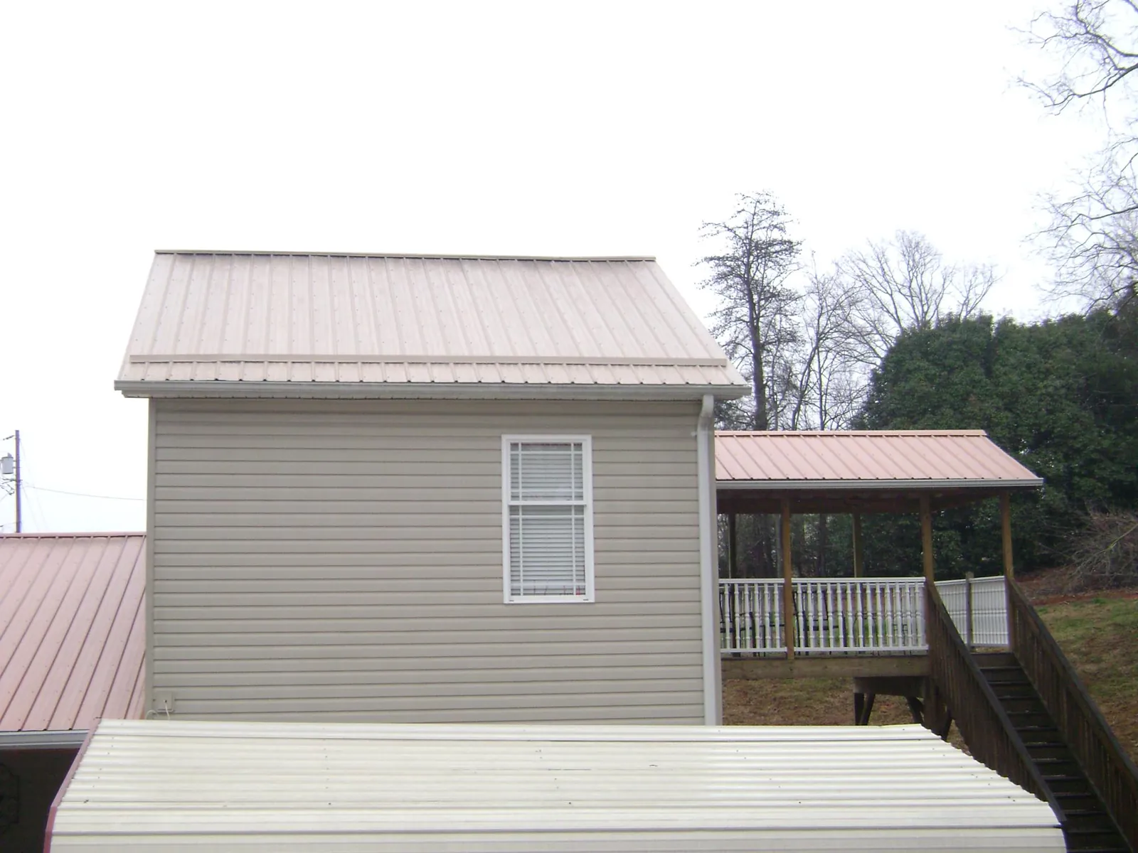 Tan metal roofs on a two story addition and attached porch, from a Roof Replacement job in Belle Mead