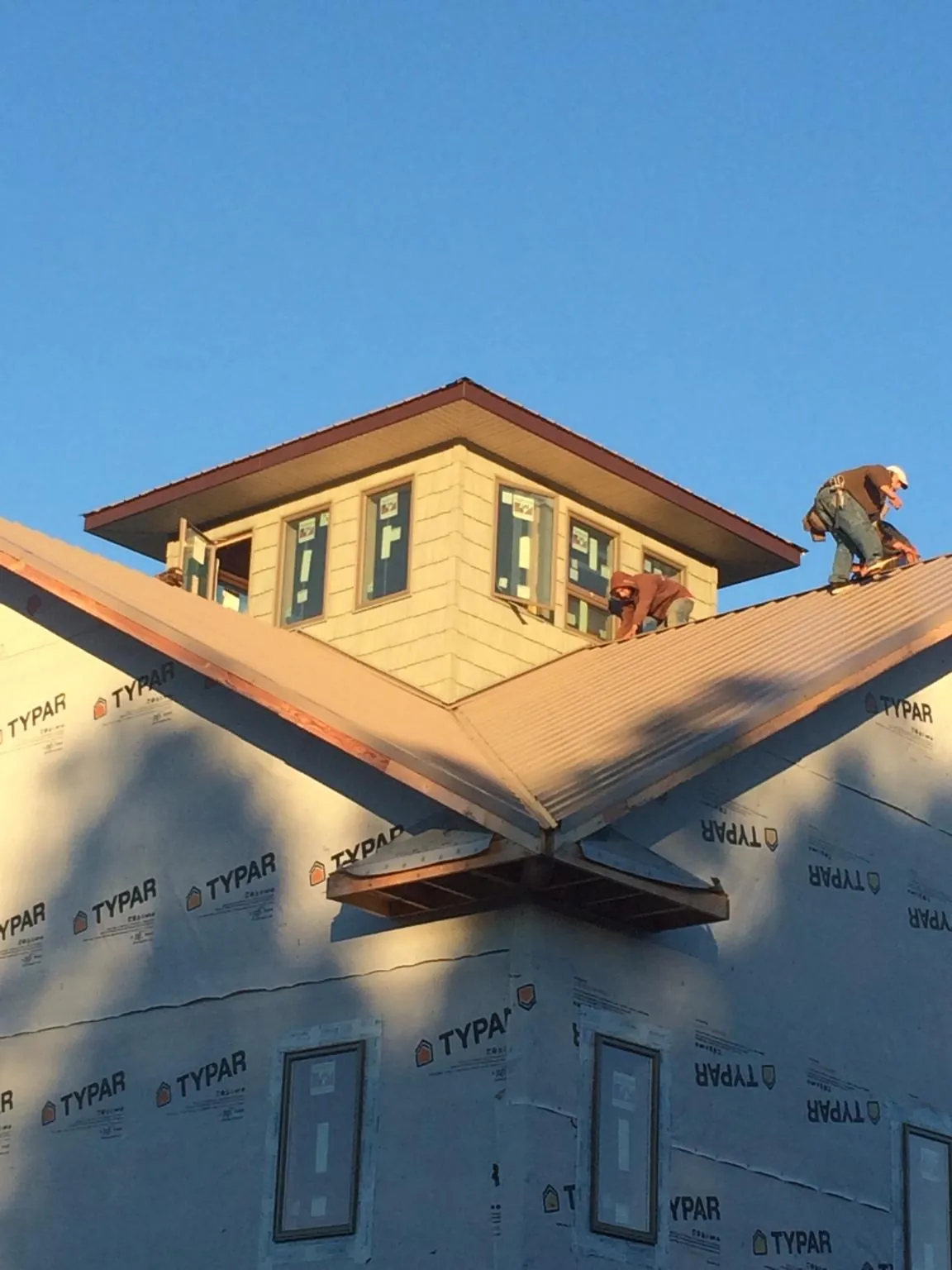 Roofers working around a rooftop cupola on a new metal roof at sunset — Roof Waterproofing in Belle Mead by Roofing Brothers